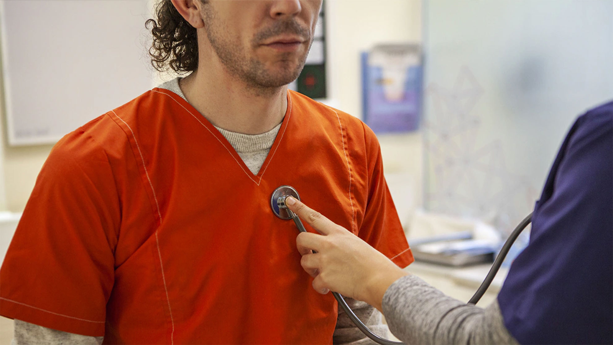 Image of incarcerated man being examined by a healthcare professional.