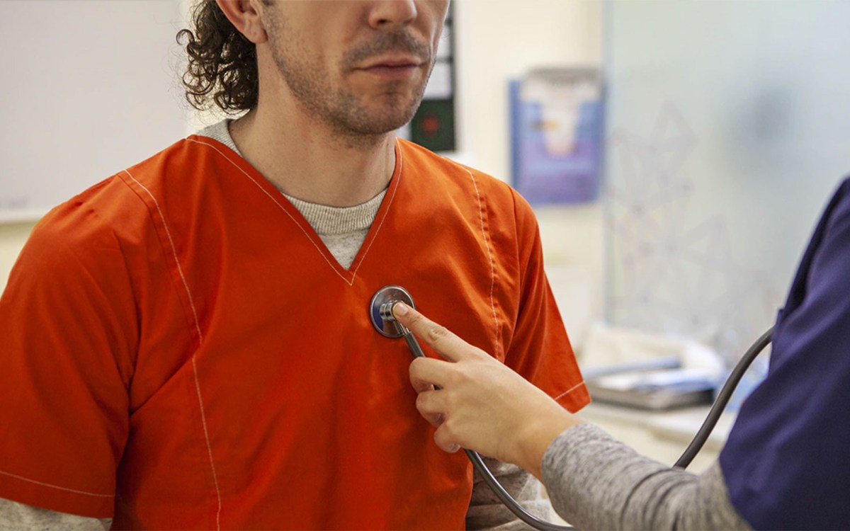 Image of incarcerated man being examined nu a doctor.