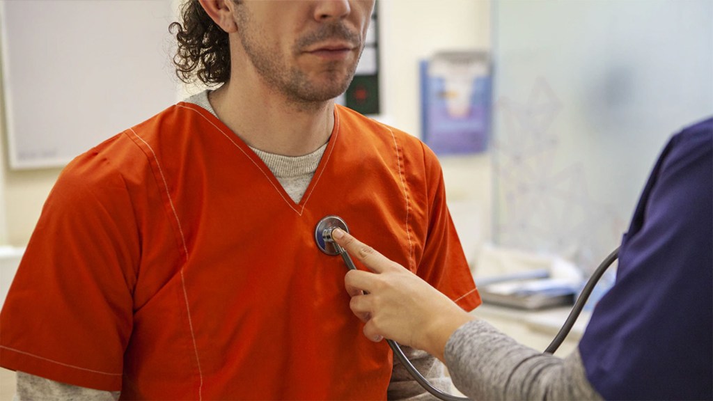 Image of incarcerated man being examined nu a doctor.