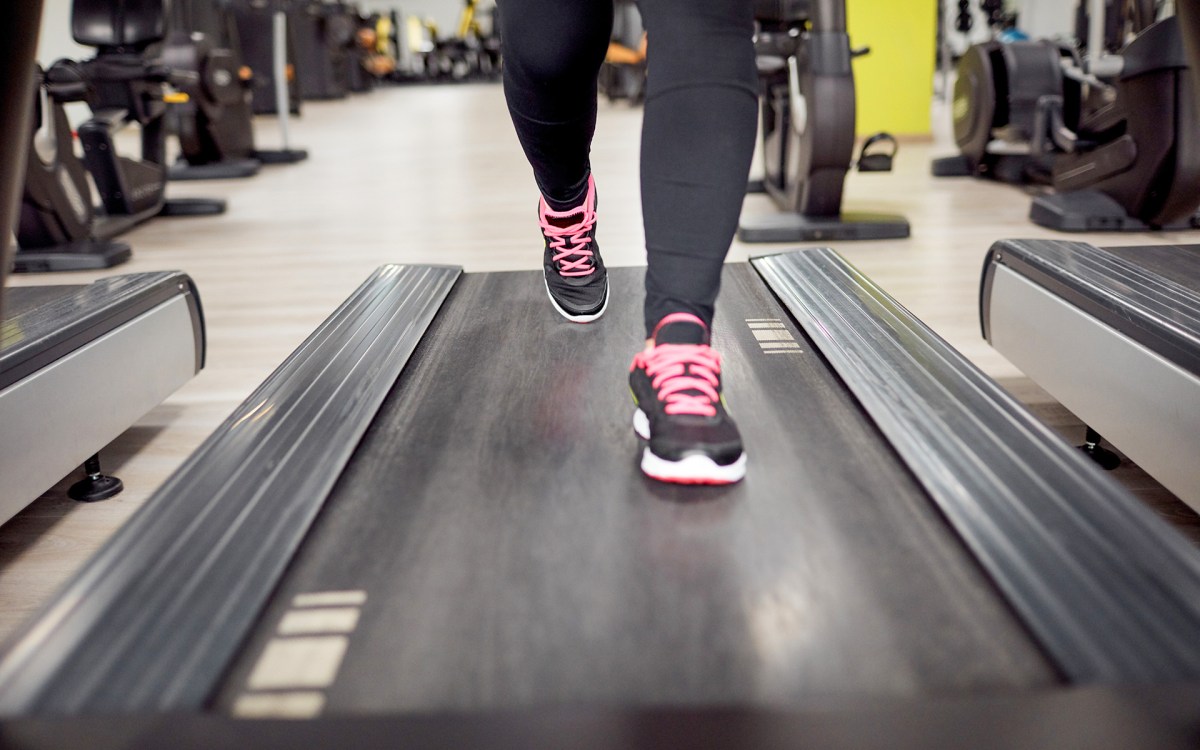 Detail of a person's legs on a treadmill in the gym.