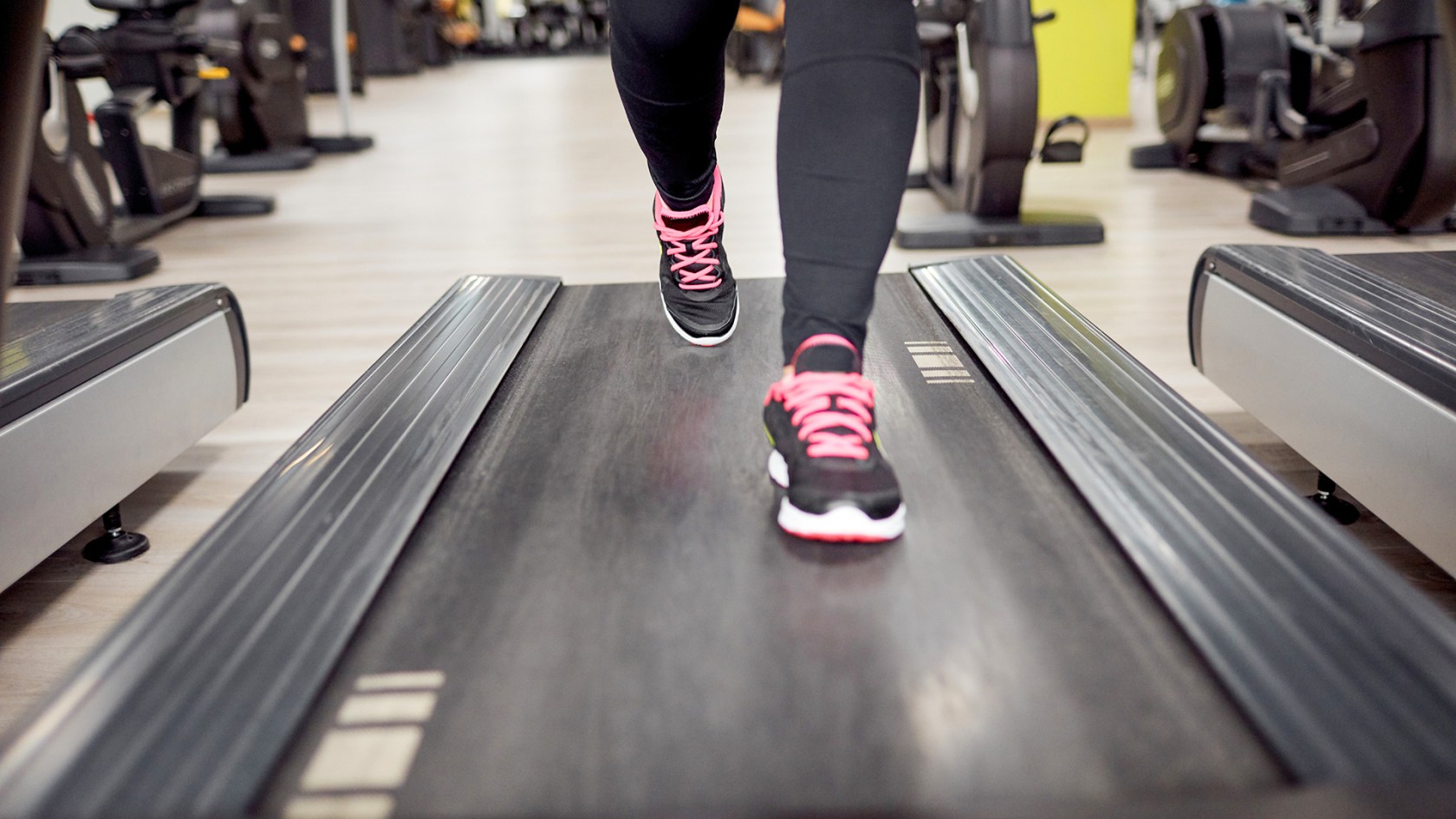 Detail of a person's legs on a treadmill in the gym.