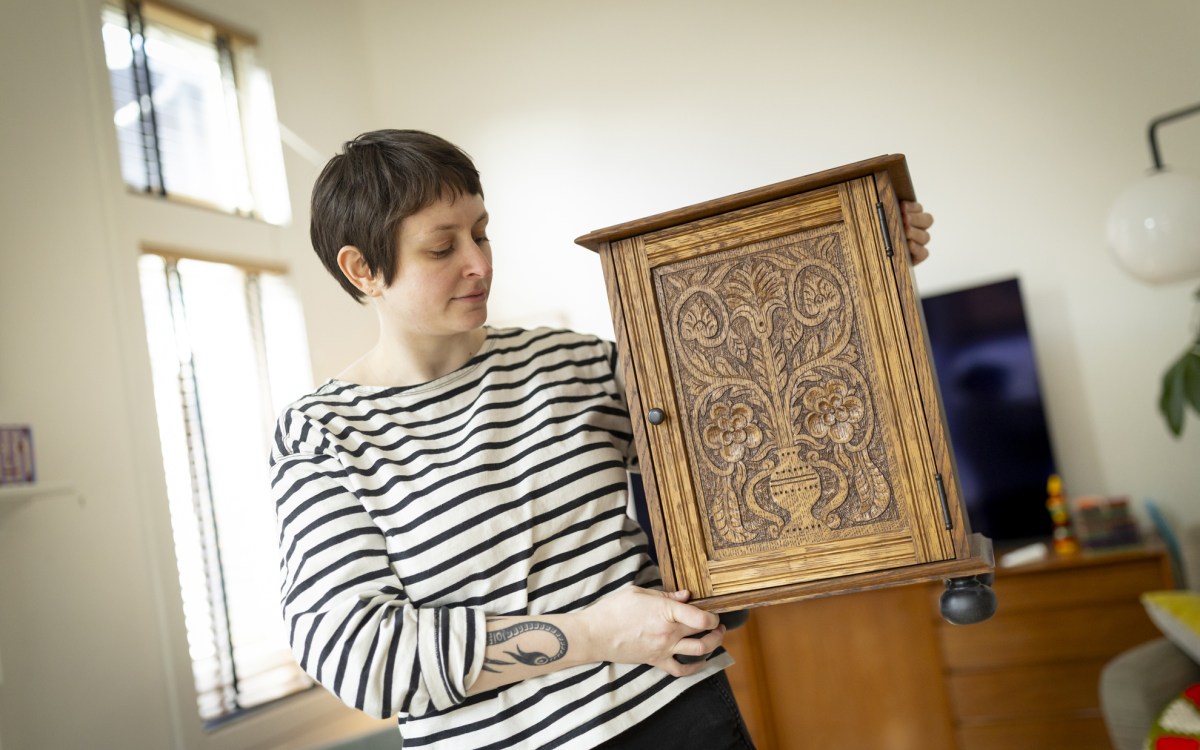 Eve Radovsky, Faculty Assistant at Harvard Law School, woodworker, and crafter poses for a photo with a cabinet she made.