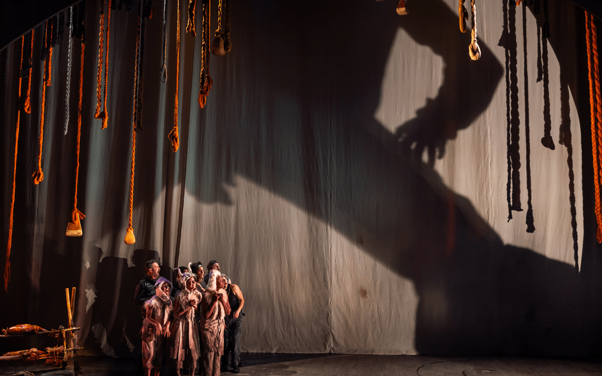 actors on stage hiding from a giant shadow