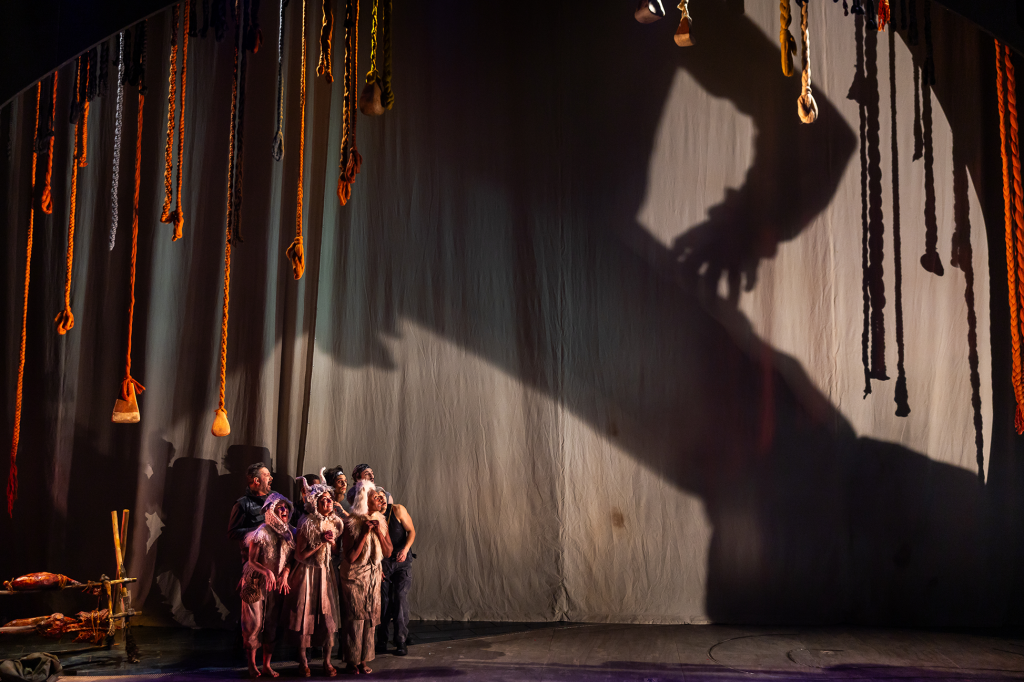 actors on stage hiding from a giant shadow