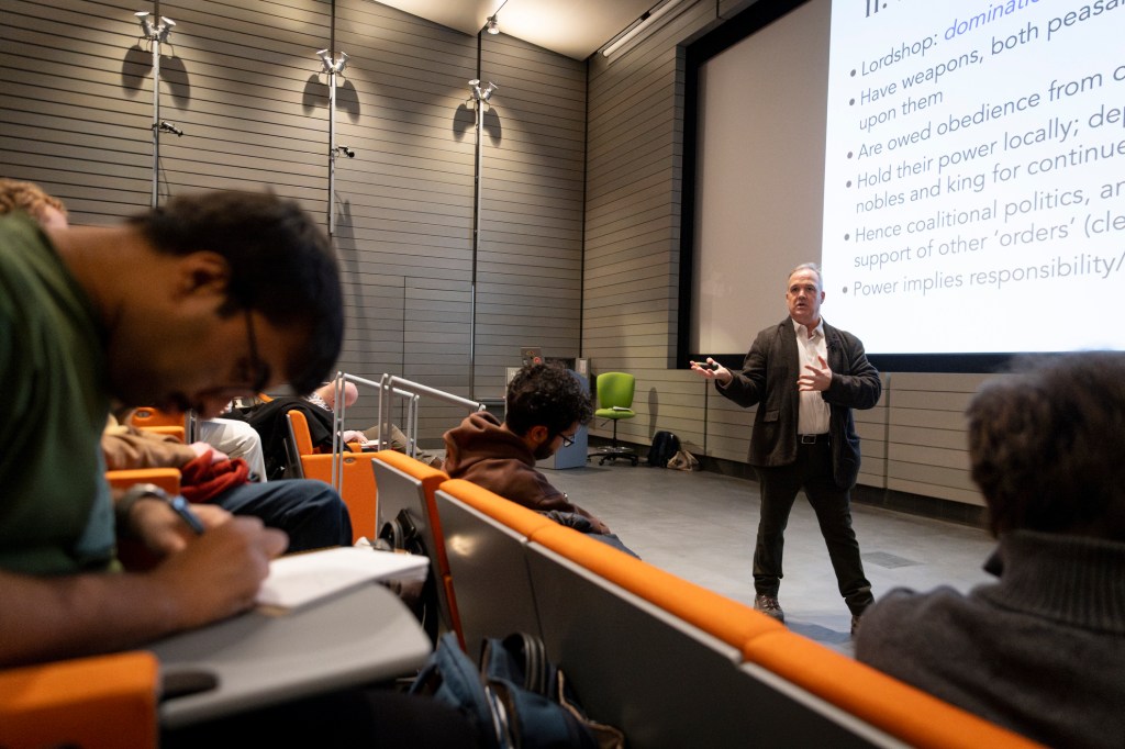 Daniel Carpenter teaching as students take notes.