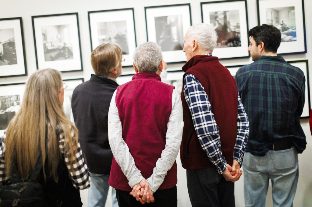 Attendees gather to examine the photographs closely following the talk.