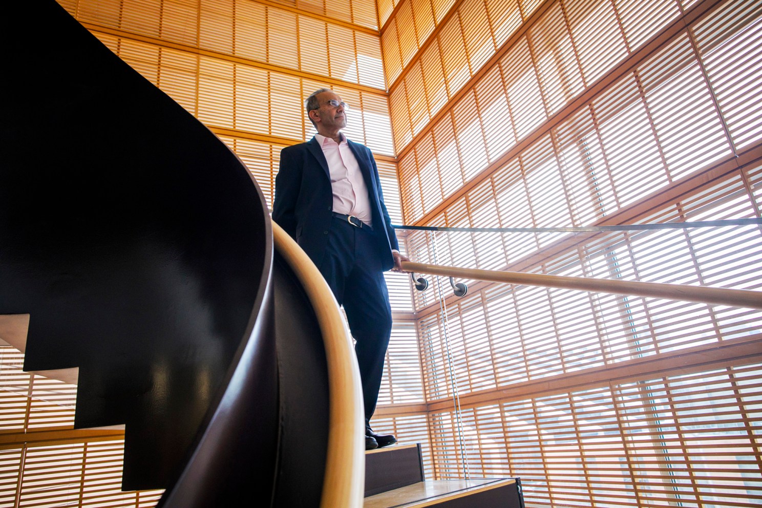 Tarun Khanna stands on a staircase in front of windows