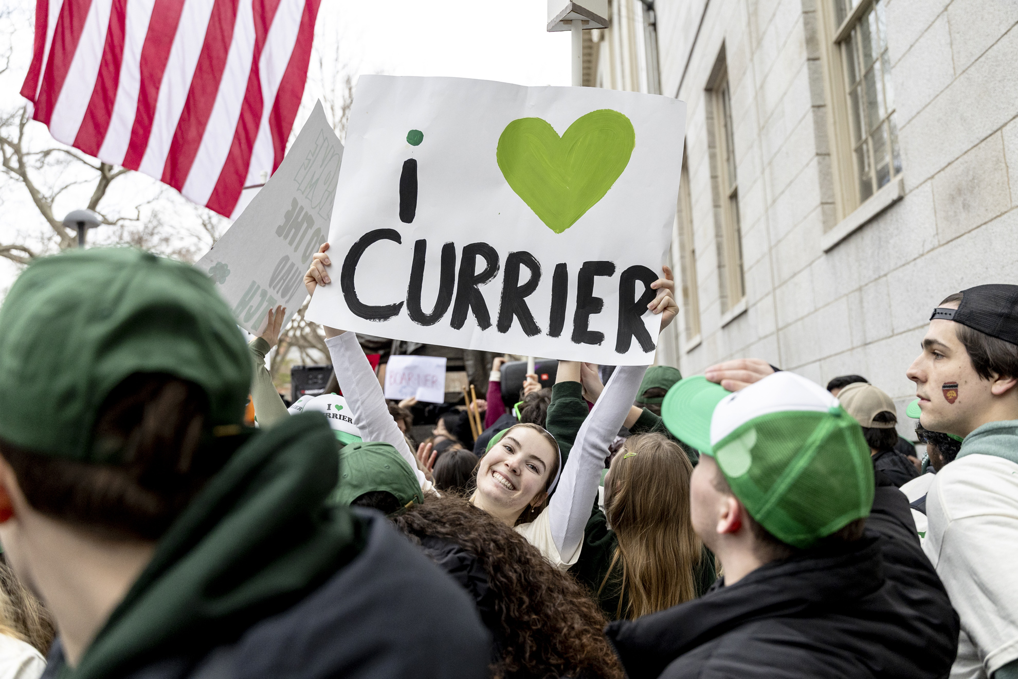 Amelie Lima ’27 holds up a Currier House sign in Harvard Yard.