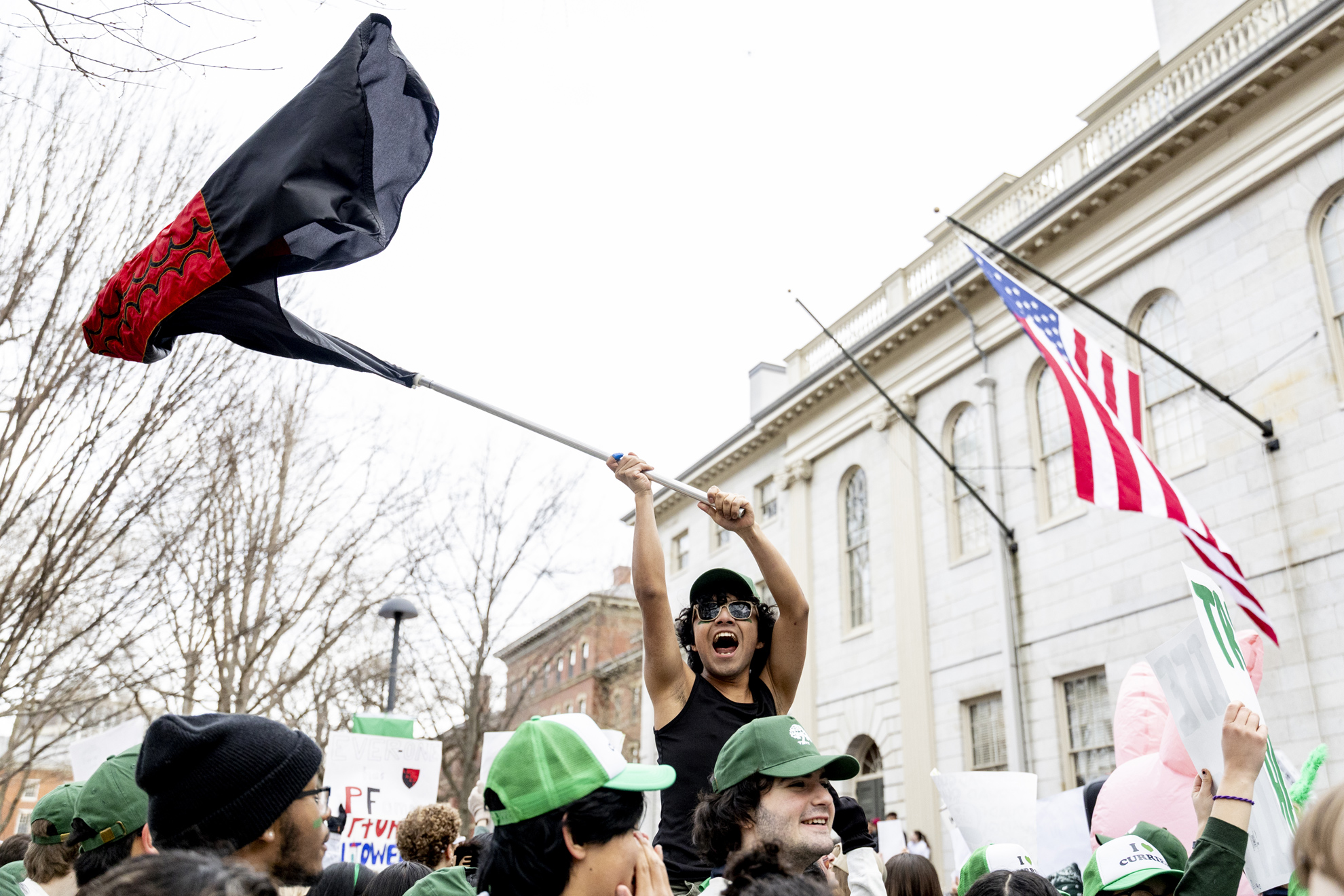 A Currier House resident waves the Currier Flag in Harvard Yard on Housing Day.