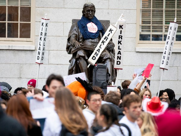 The John Harvard statue, surrounded by Kirkland House signs, is seen during the annual Housing Day tradition in Harvard Yard.