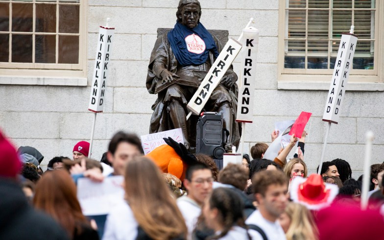 The John Harvard statue, surrounded by Kirkland House signs, is seen during the annual Housing Day tradition in Harvard Yard.