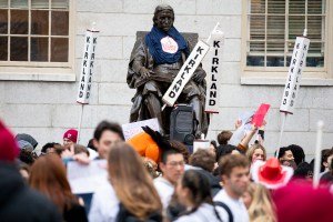 The John Harvard statue, surrounded by Kirkland House signs, is seen during the annual Housing Day tradition in Harvard Yard.