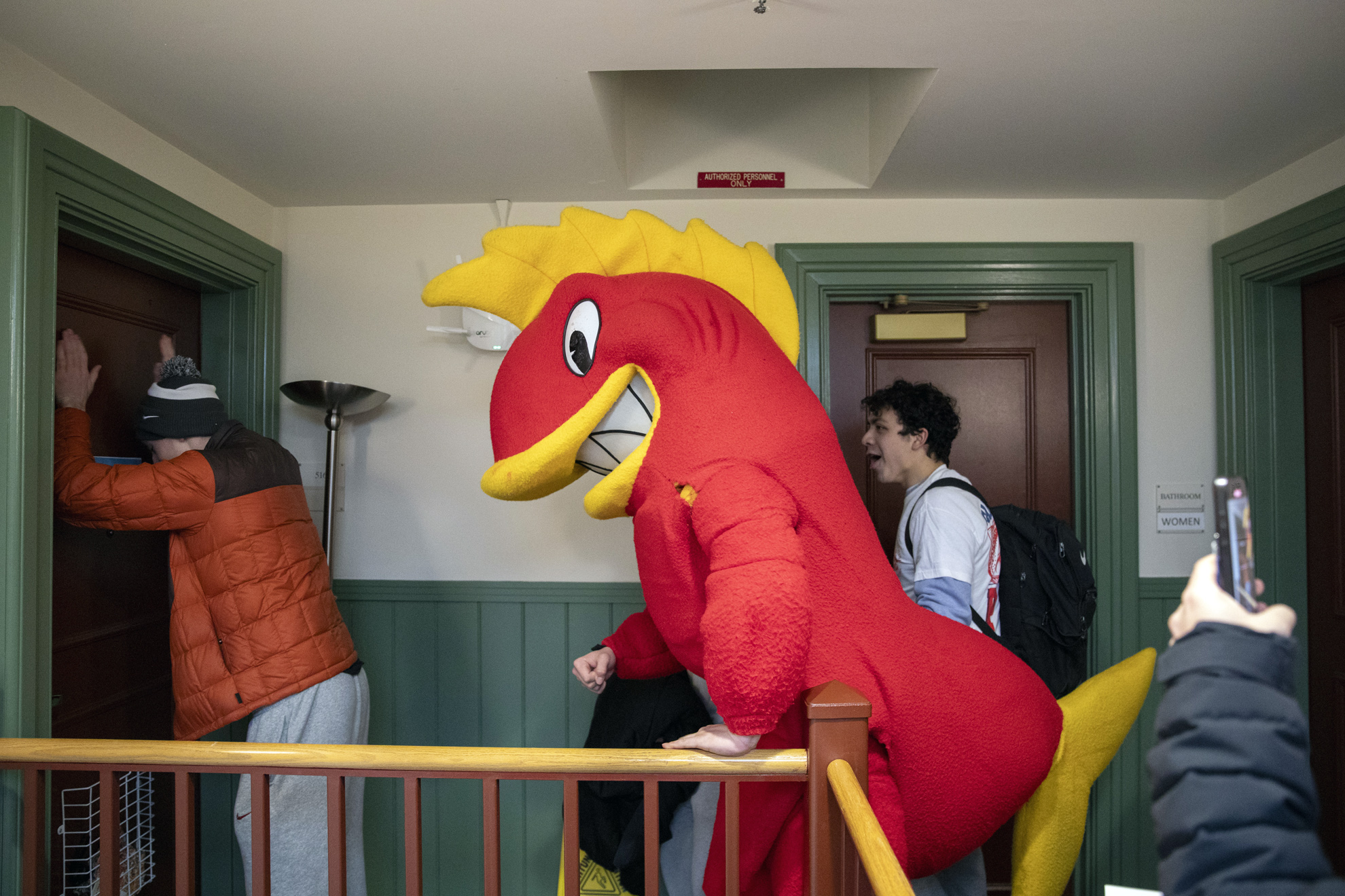 Max Wagner, ’27, dressed as a fish, Cabot House’s mascot, prepares to enter a first-year dorm room to notify a resident about their housing placement.