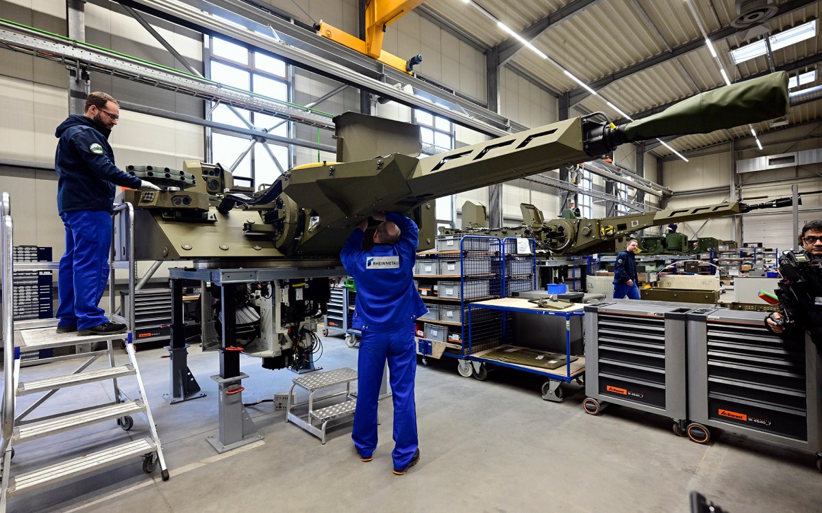 Employees at a munitions factory in Germany work on weapons in a production line.