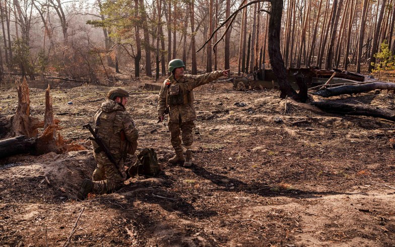 Ukrainian soldiers install explosives in a clearing in the woods.