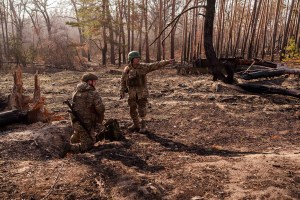 Ukrainian soldiers install explosives in a clearing in the woods.