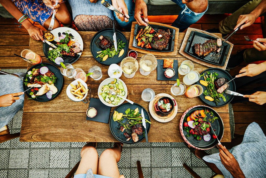 Friends sitting around a table eating together.