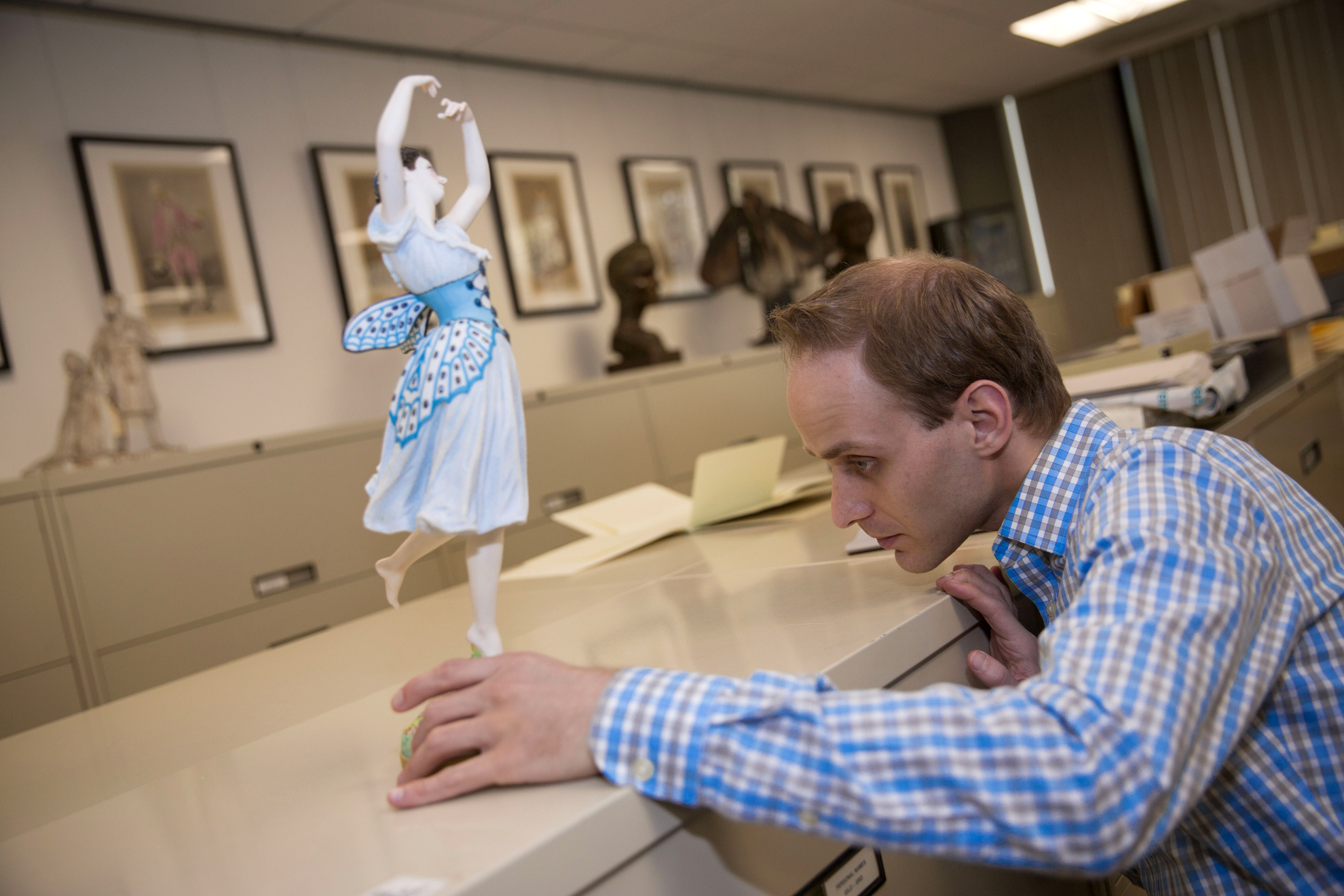 Dale Stinchcomb, Curatorial Assistant examines a Figurine by Jean Auguste Barre of the young French ballerina Emma Livry (1842-1863) in "Le Papillon" (The Butterfly), in the Harvard Theatre Collections.