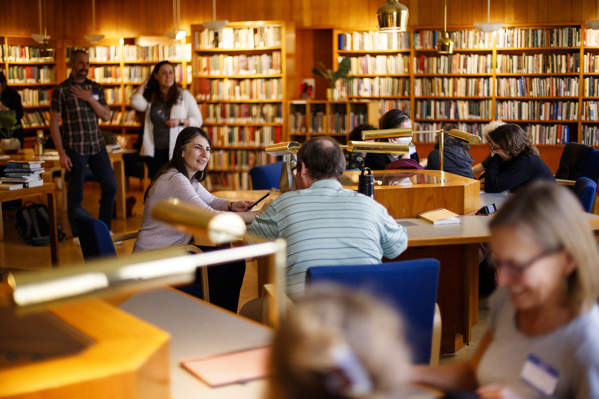 Writers look through bookshelves and sit around tables in the Woodberry Poetry Room.