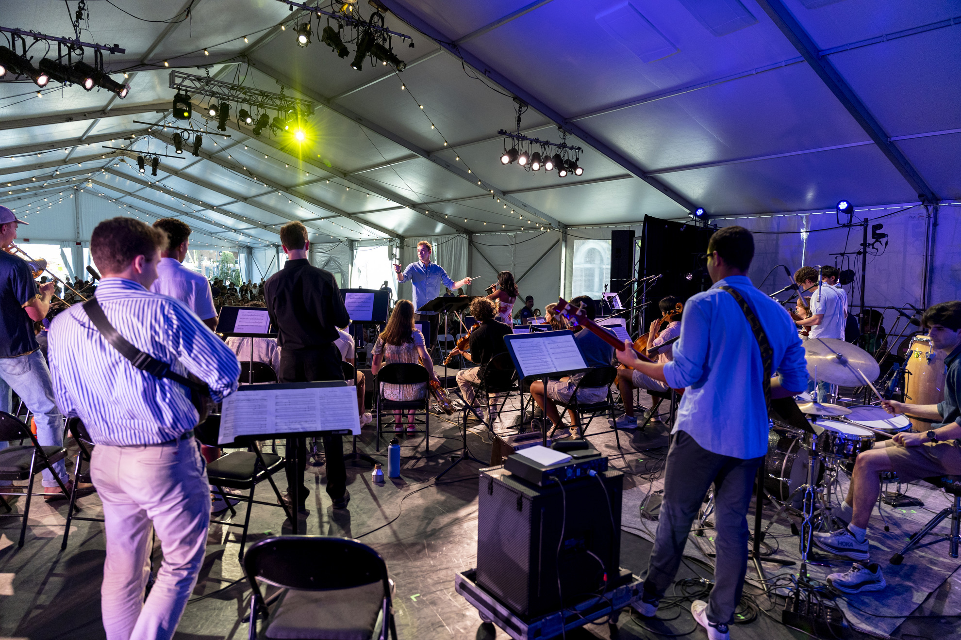 Emil Massad ’25 conducts the Charles Revival and Friends performance at the Science Center Plaza tent.