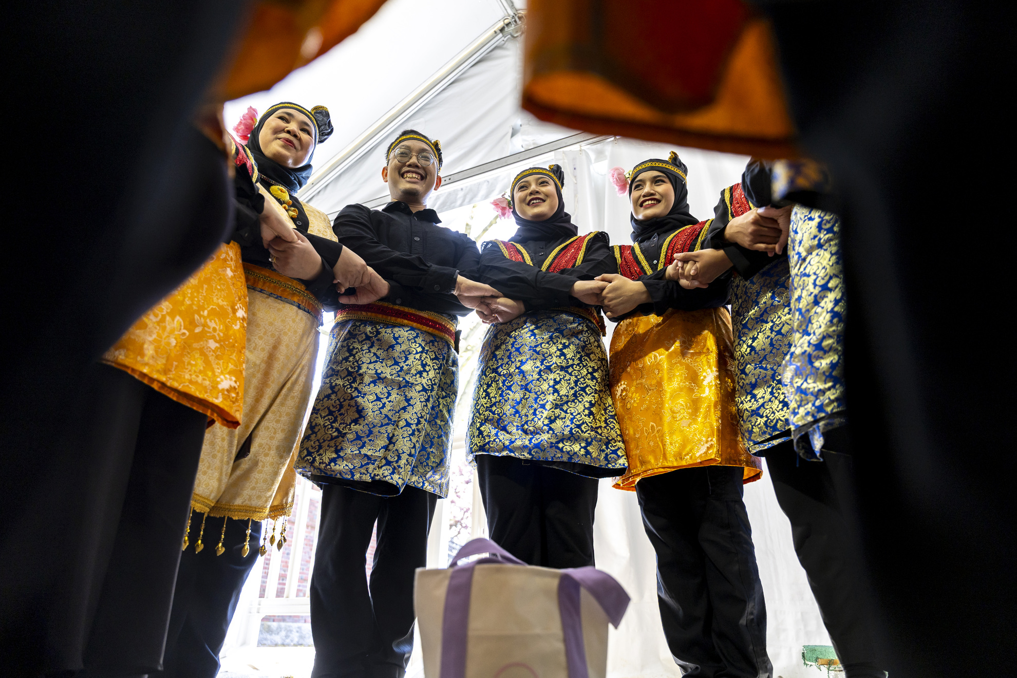 Members of the Boston Cendrawasih huddle before their performance at the Science Center Plaza Tent.