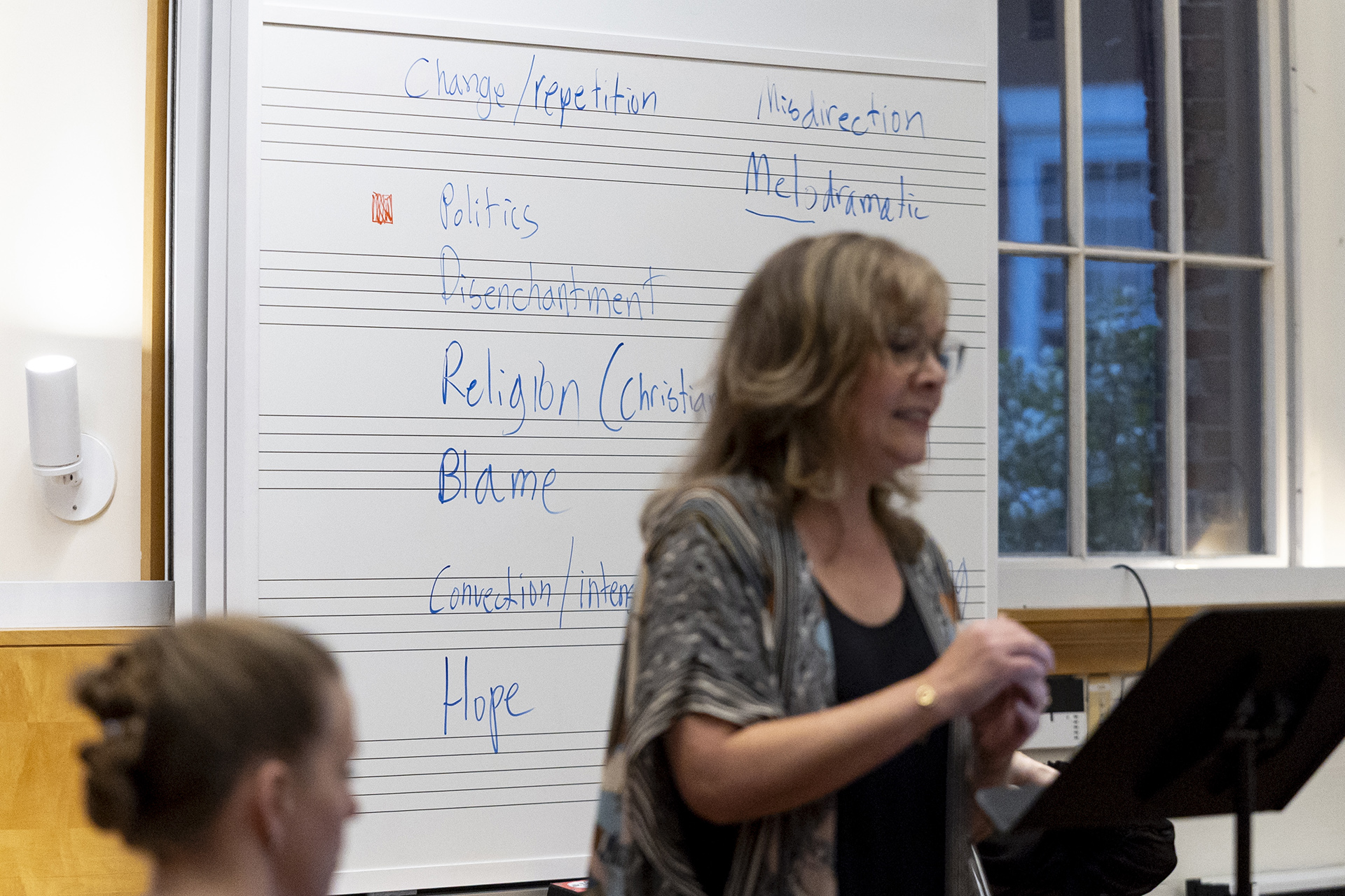 Singer Krista River in front of a white board containing words such as "change," "politics," "disenchantment," and relgiion."