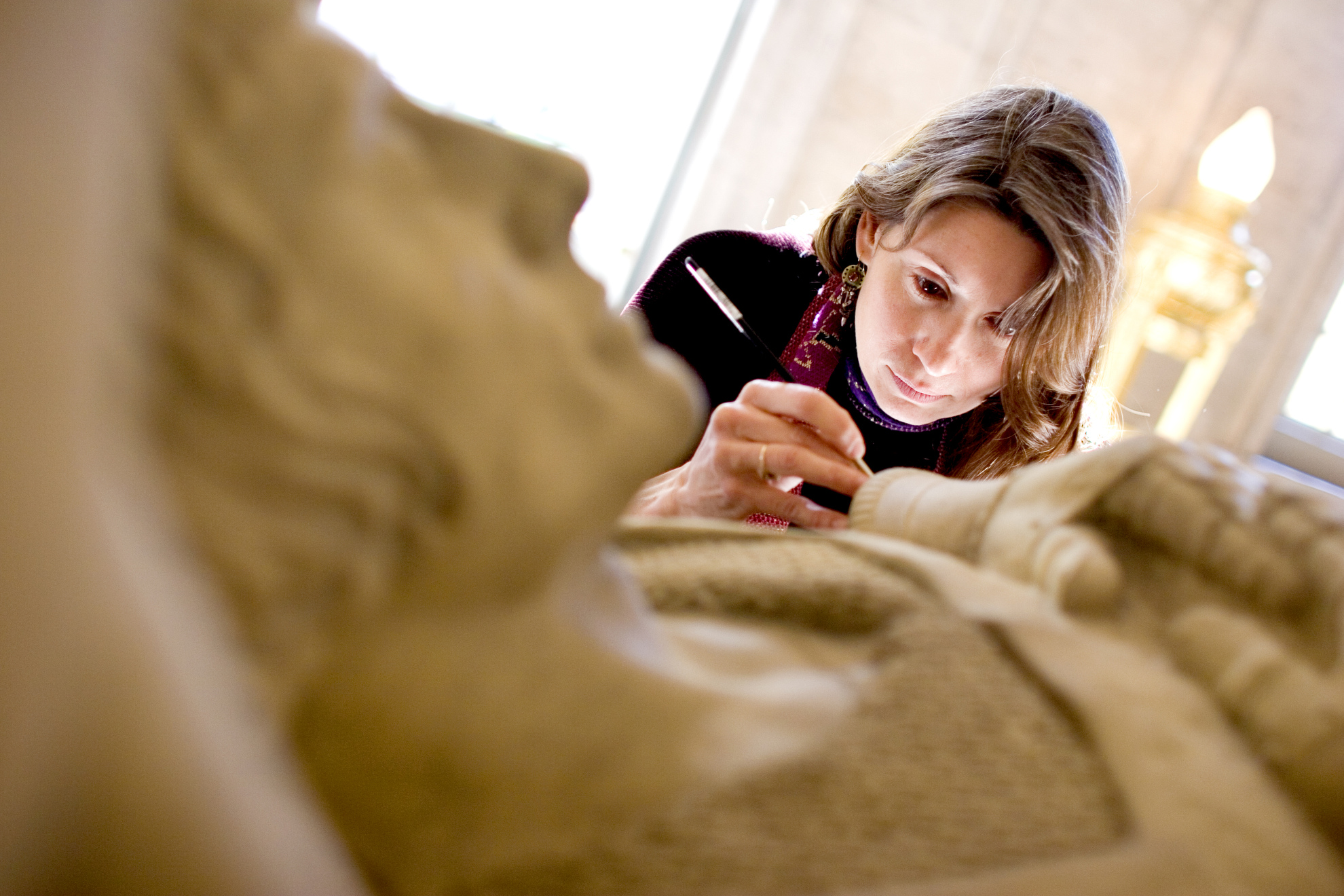 Nancy Lloyd, Objects Conservator for the Straus Center for Conservation at Harvard University, restores the fallen soldier statue in the Memorial Room at Memorial Church.