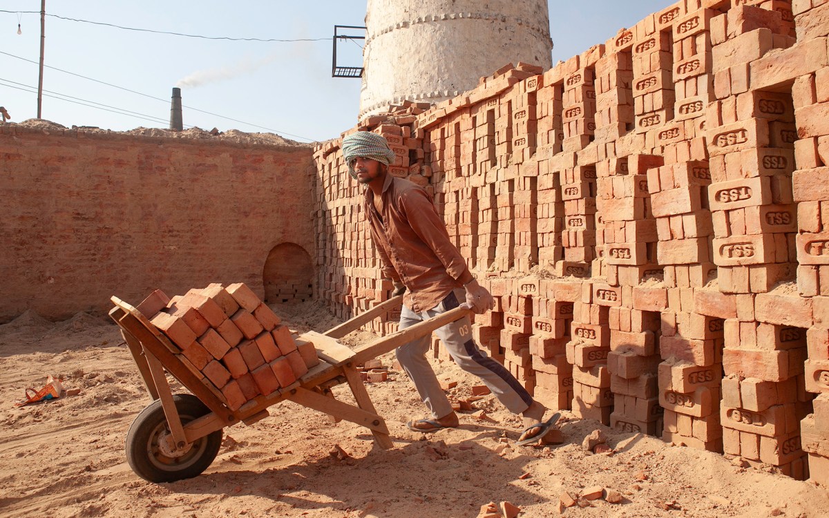A man wheels bricks from a kiln under intense heat in India.
