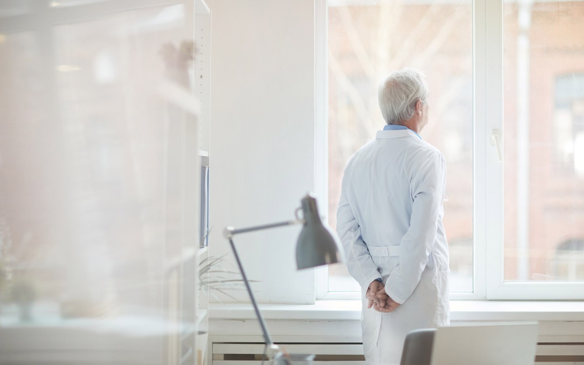 Older doctor looking out of a window.