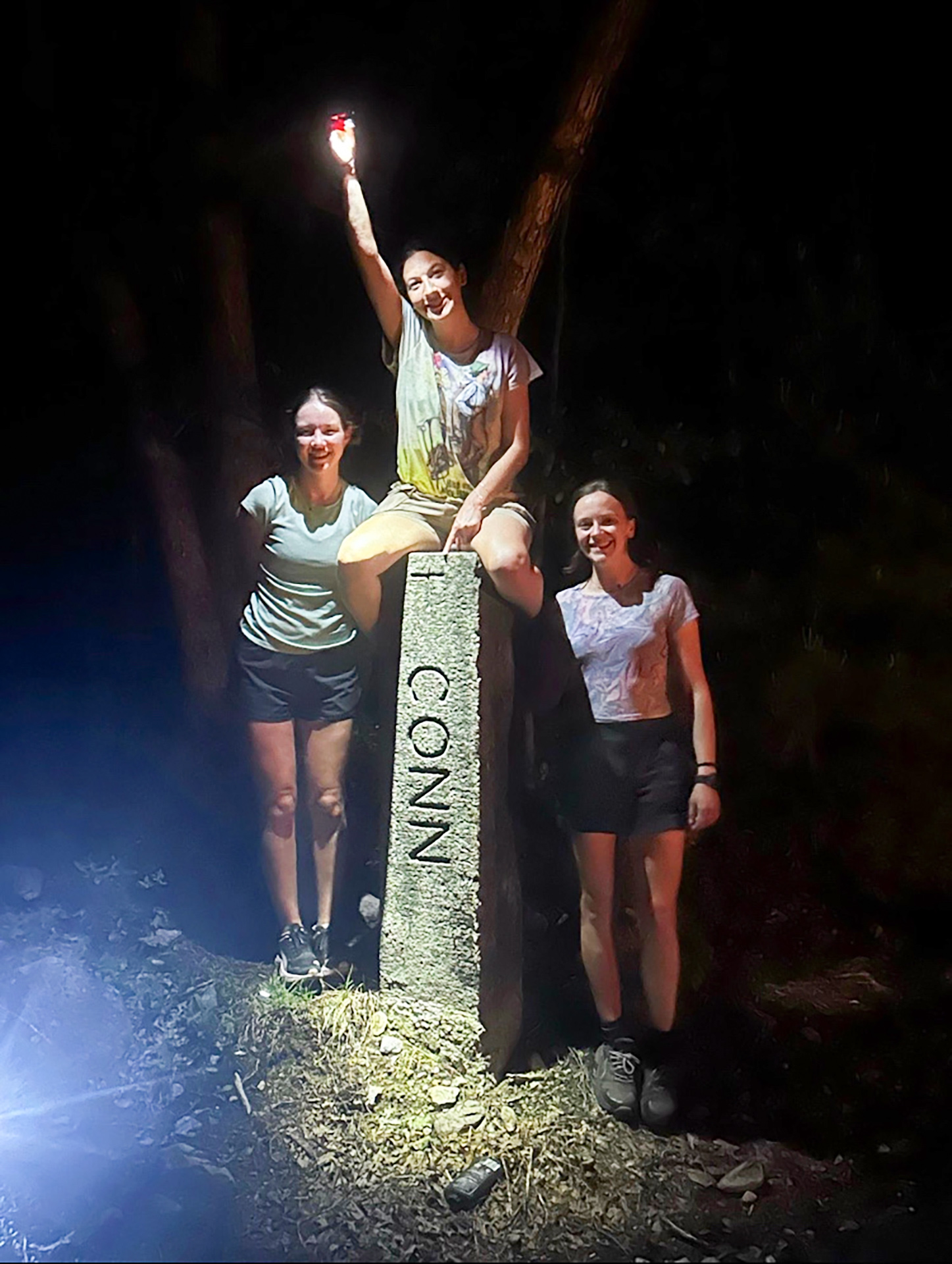 Eden Fisher, Amelia Heymach, and Addie Kelsey pose by a Connecticut milepost.