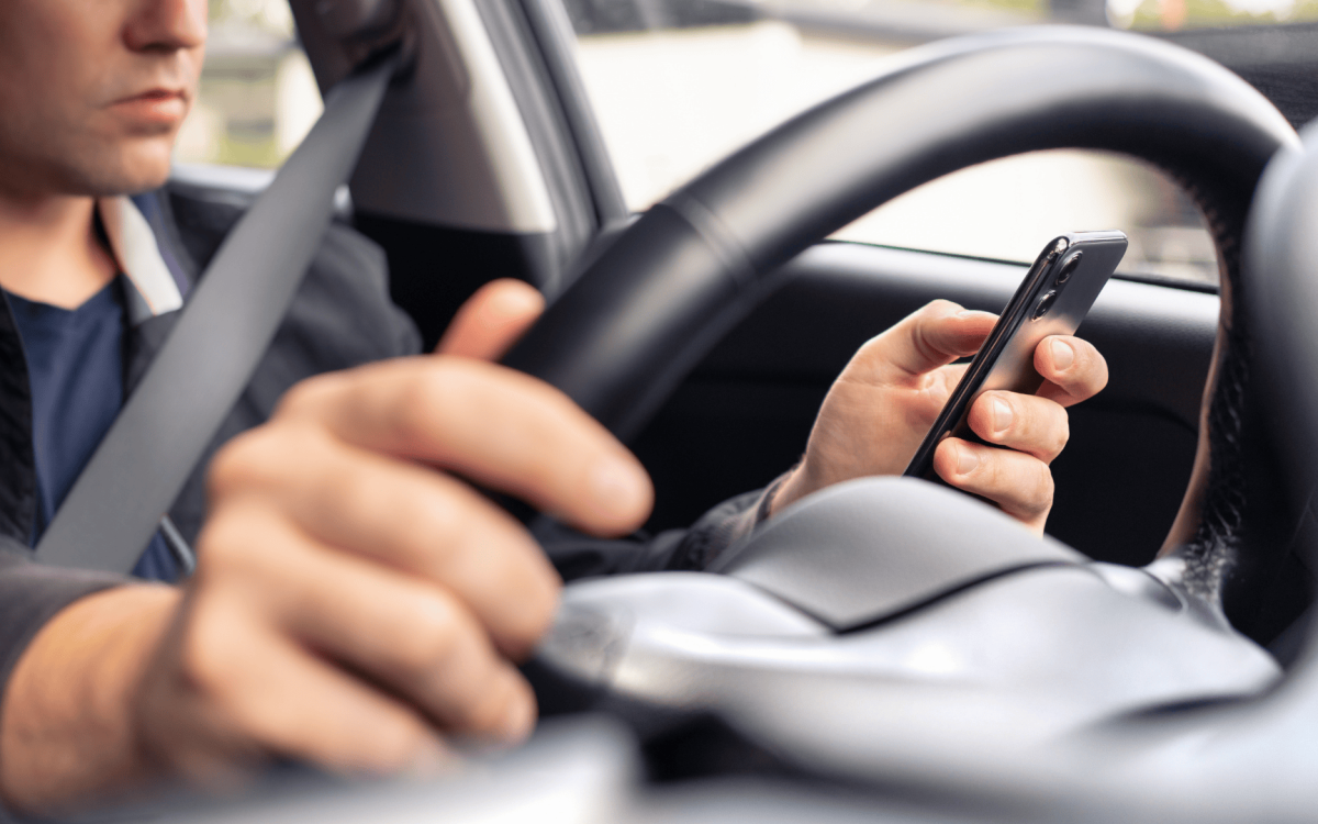 person looking at their phone while driving
