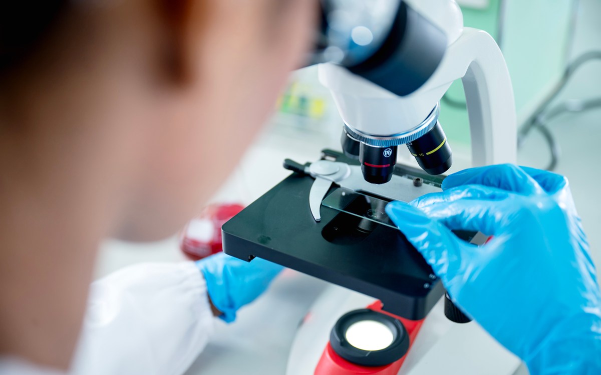 A scientist uses a microscope in a lab.