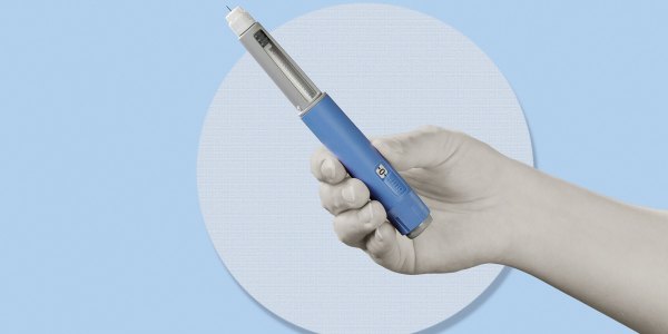 Hand holding semaglutide injection pen.