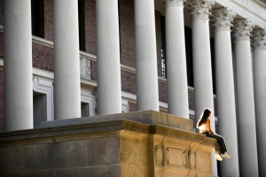 A person sits atop the steps of Widener Library.