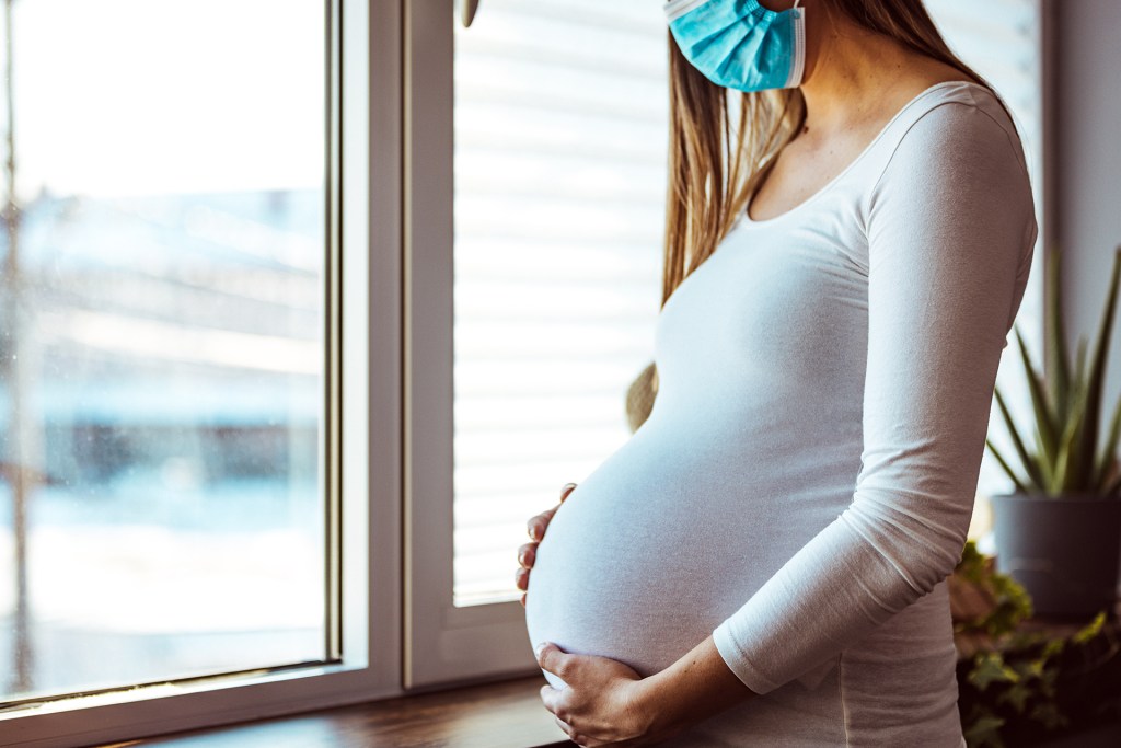 Pregnant woman wearing medical mask.