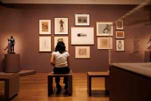 a woman sitting in front of a gallery wall