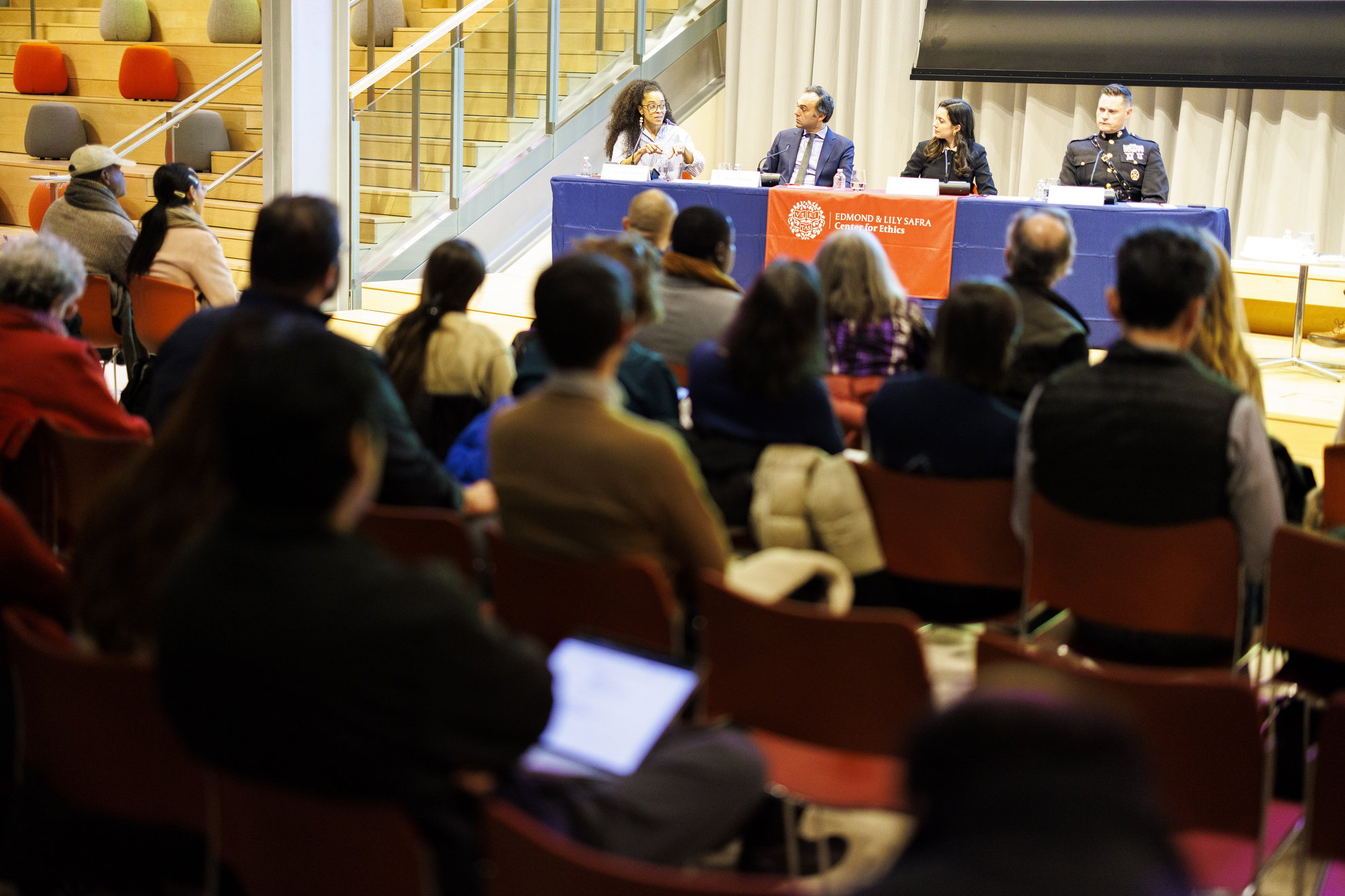 Panelists sit in front of an audience.