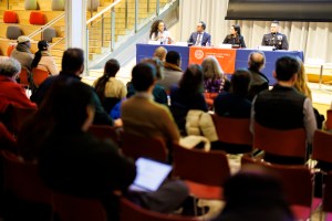 Panelists sit in front of an audience.