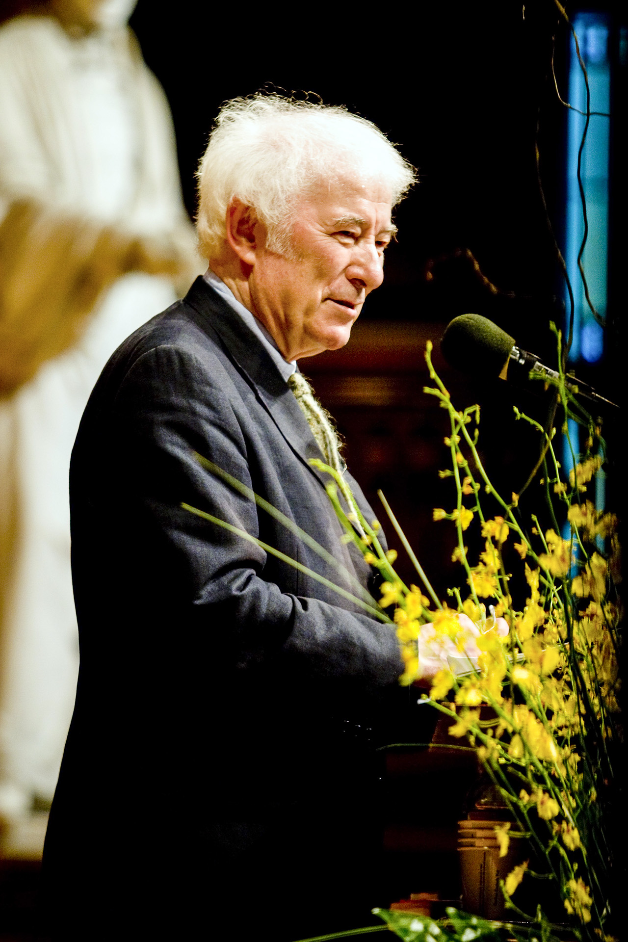 Seamus Heaney at lectern reading.