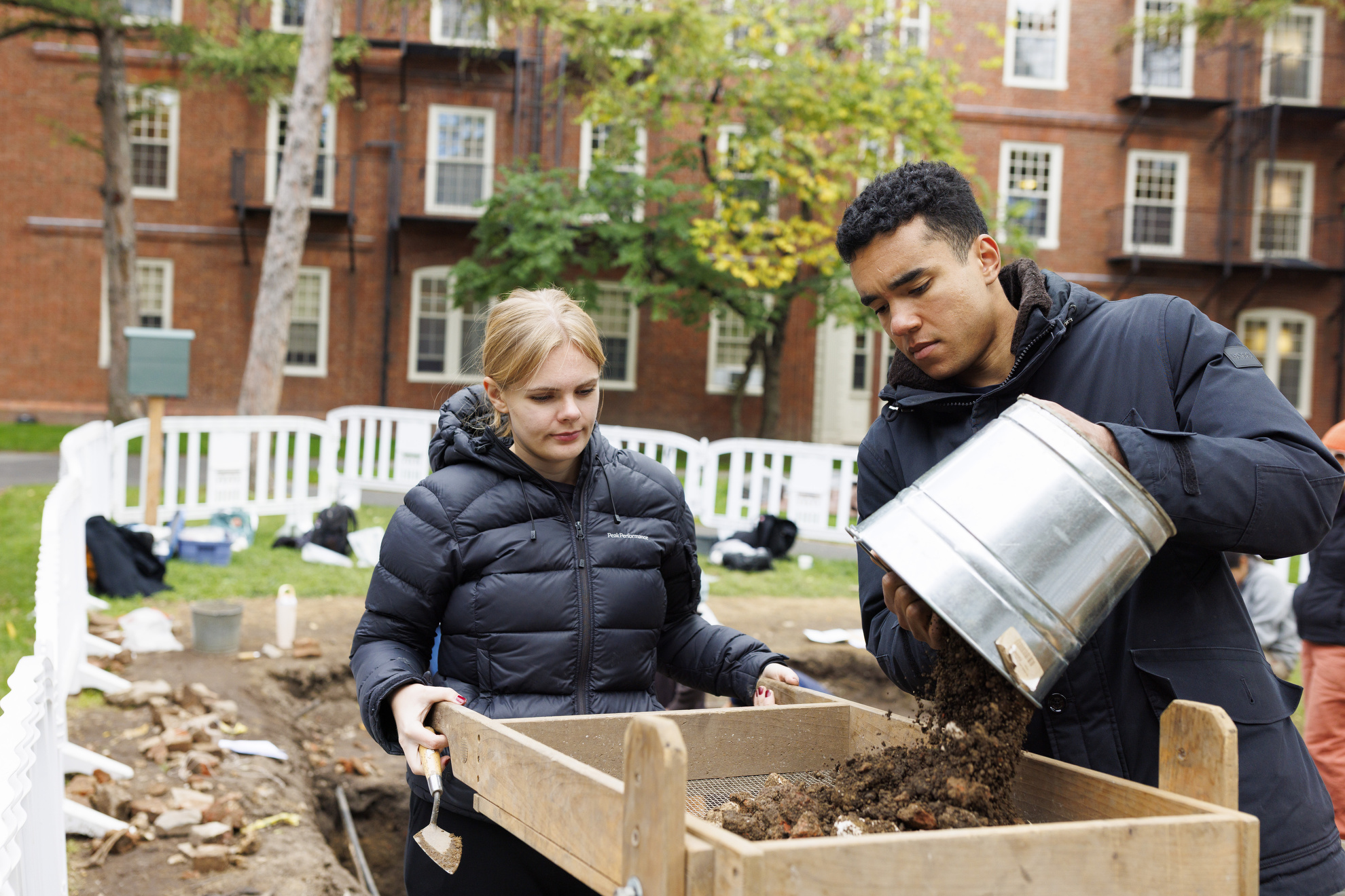 Students Jonas Freeman (right) and Nina Skov Jensen use a sifting screen to search debris for artifacts.