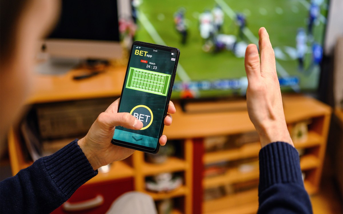 Man using betting app on his smartphone.