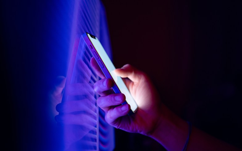 Person holding a smartphone in the dark.