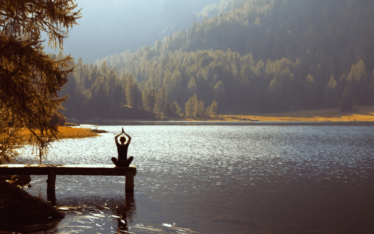 person meditating at lake