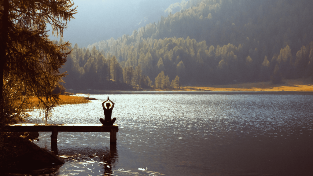 person meditating at lake