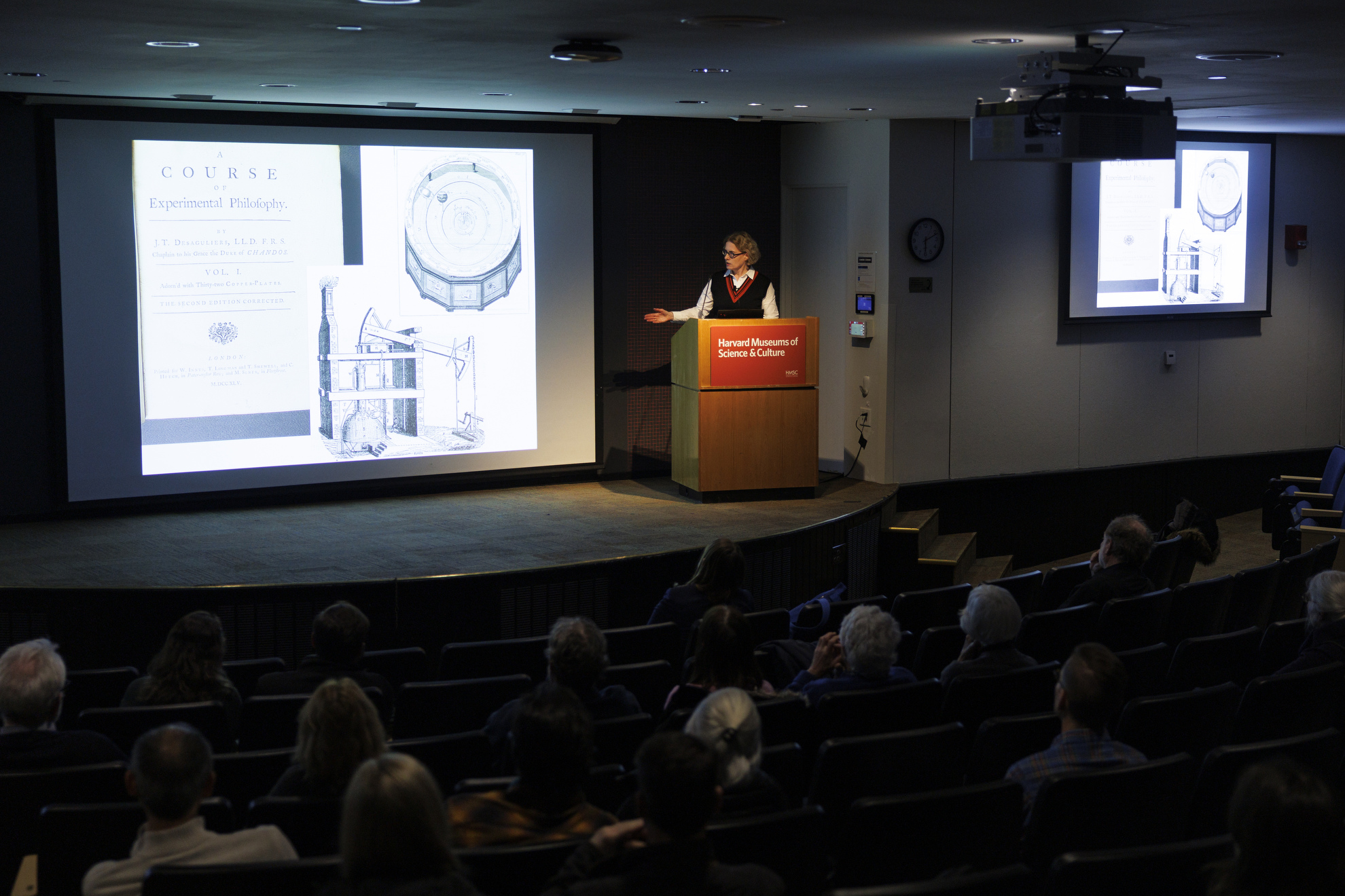 Joyce Chaplin in front of a screen onstage.