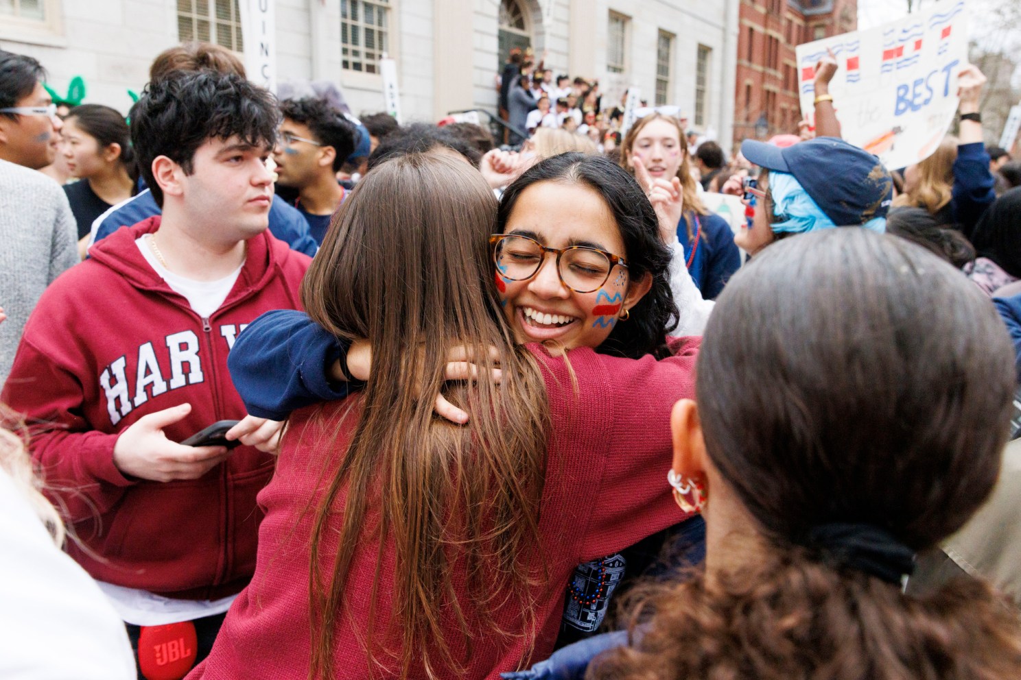 Akshaya Ravi ’27 (center) hugs a classmate during the annual Housing Day tradition in Harvard Yard. 