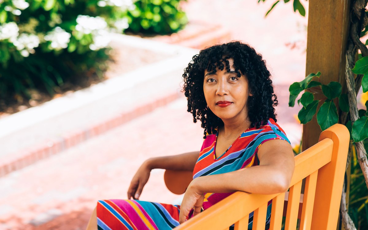 Namwali Serpell sitting on a bench outside.