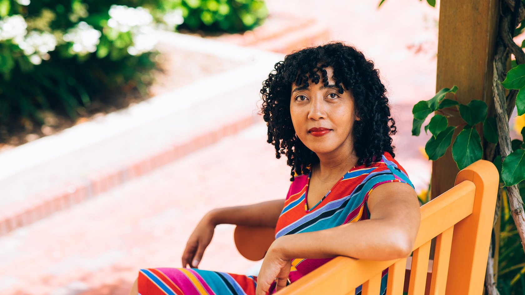 Namwali Serpell sitting on a bench outside.