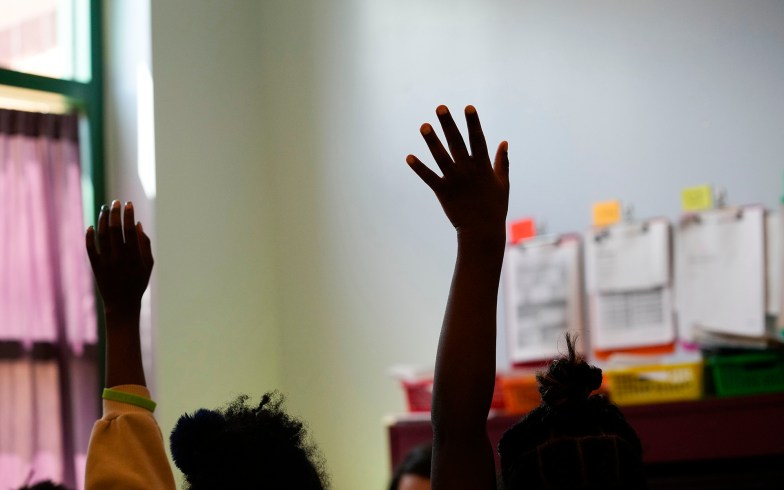 Third-graders in a New Orleans classroom raise their hands.