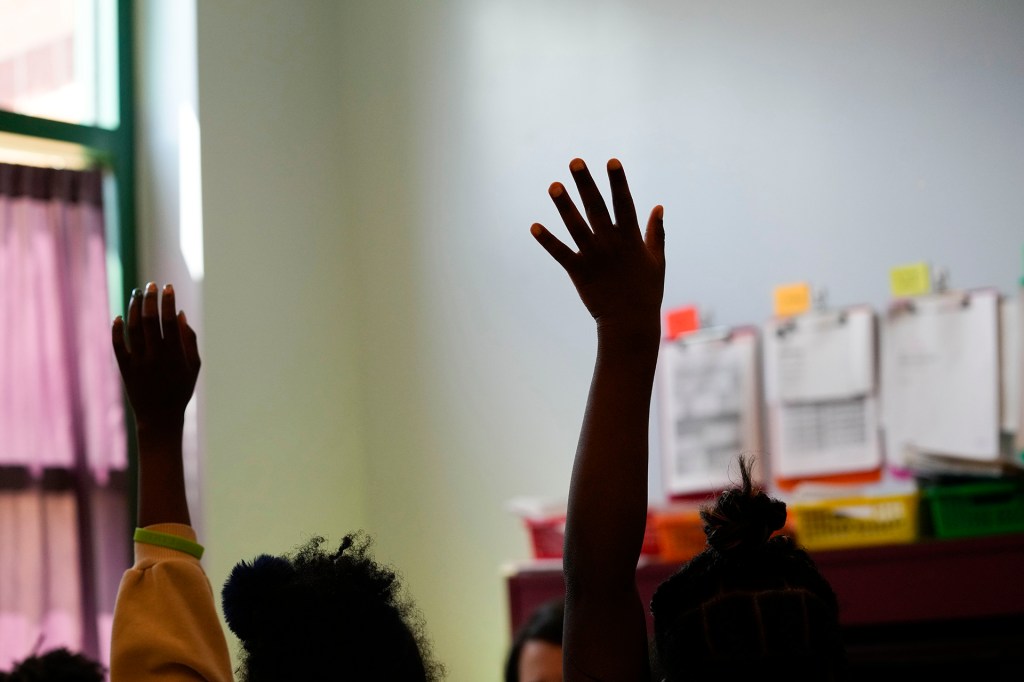Third-graders in a New Orleans classroom raise their hands.